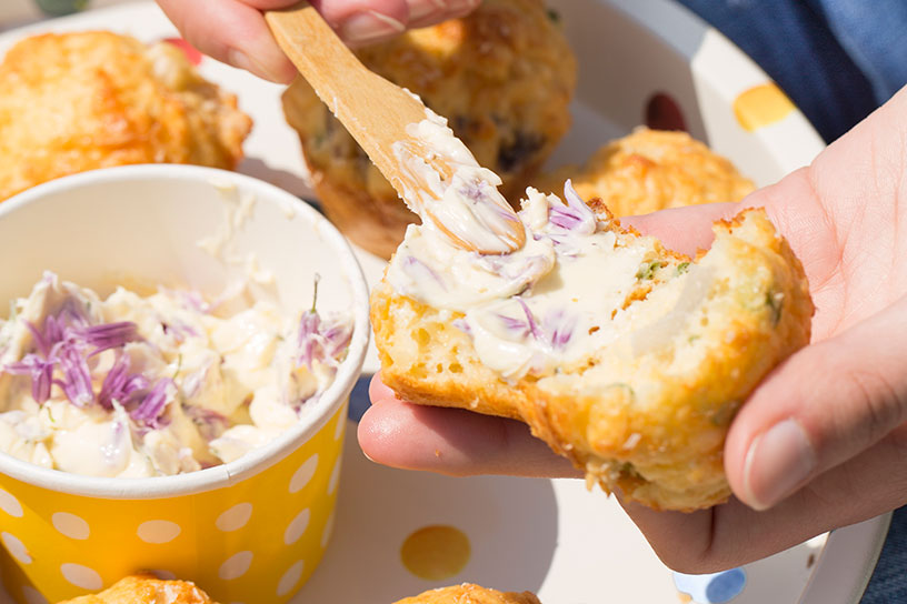 Bieslookbloemetjesboter smeren op hartige lente-uimuffins